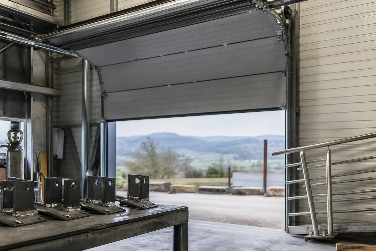 Porte sectionnelle industrielle relevée au plafond d&rsquo;un atelier de production